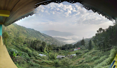 Mountain views framed by the homestay’s wooden balcony, with lush green forests below.