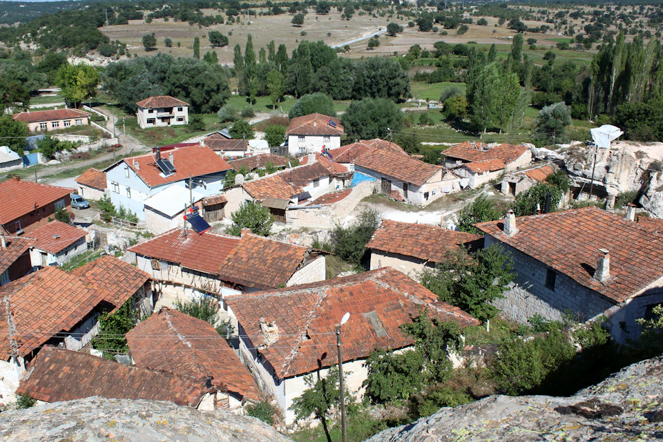 Village nestled in lush greenery with red tile roofs on a hillside overlooking the valley