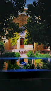 Sunlit courtyard of a traditional Moroccan riad with intricate tilework and lush greenery.