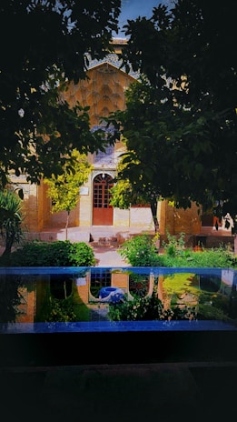A serene view of a traditional Moroccan riad’s courtyard garden with lush greenery and blue mosaic tiles.