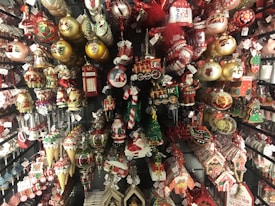 A variety of colorful Christmas ornaments and decorations arranged on shelves, including Santa figurines, nutcrackers, baubles, candy canes, mini trains, and stockings. The ornaments are in vibrant shades and depict traditional holiday themes.