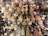 An assortment of decorative ballerina ornaments is displayed on hooks. The ballerinas are adorned with detailed tutus in various colors including pink, white, and gold, and some are embellished with glitter. Surrounding them are complementary decorative items like embroidered fabric and floral designs.