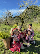 Smiling children playing in a sunlit field with saffron-colored scarves.