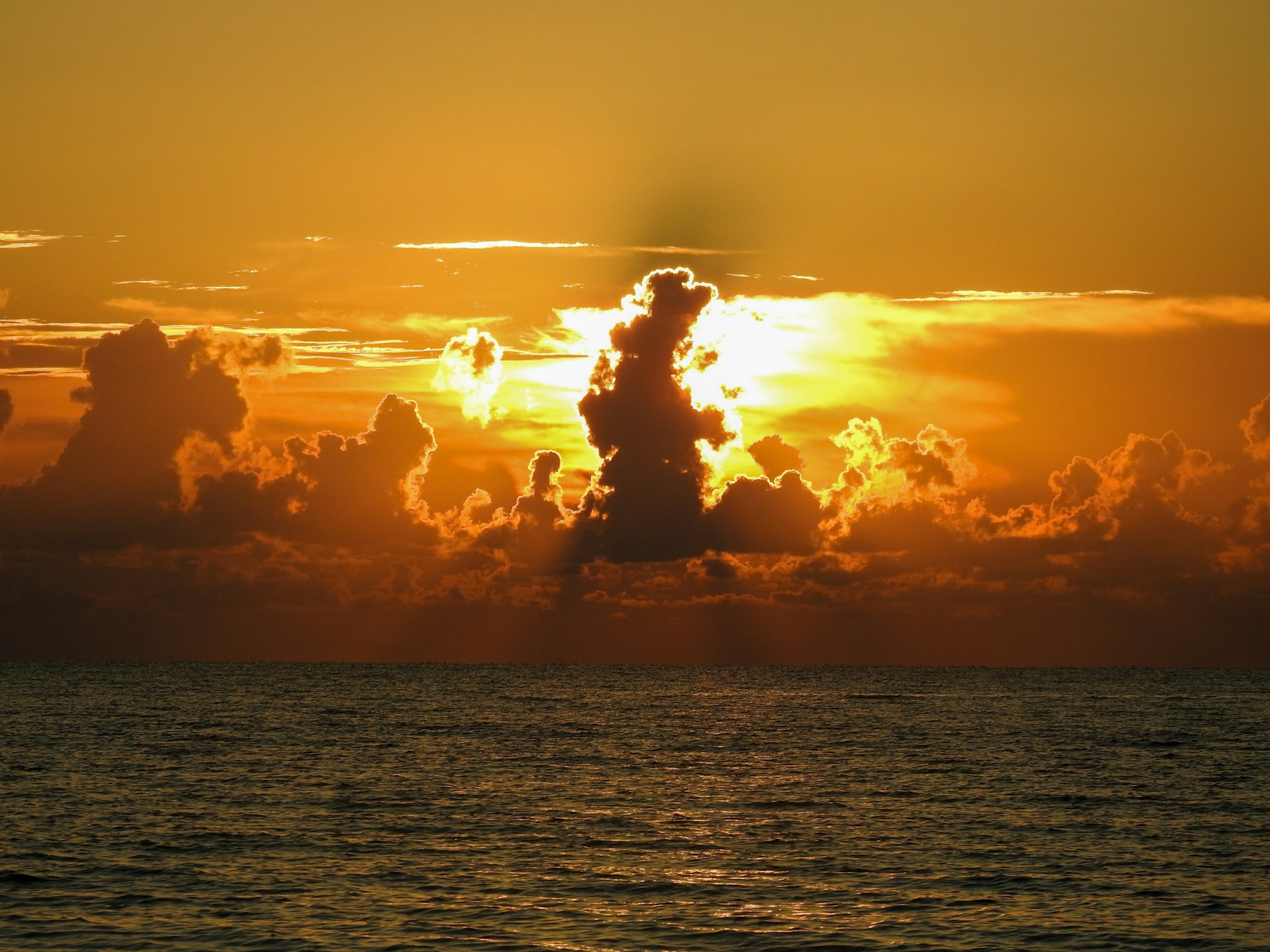 the sun is setting over the ocean with clouds