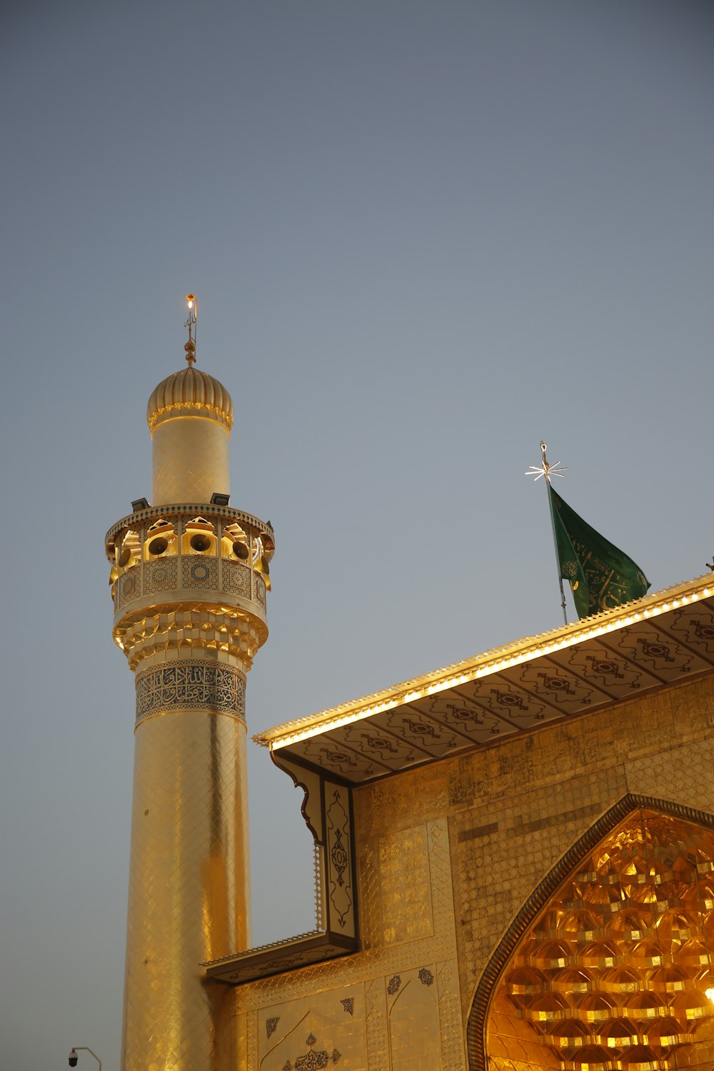 a tall golden building with a green flag on top of it