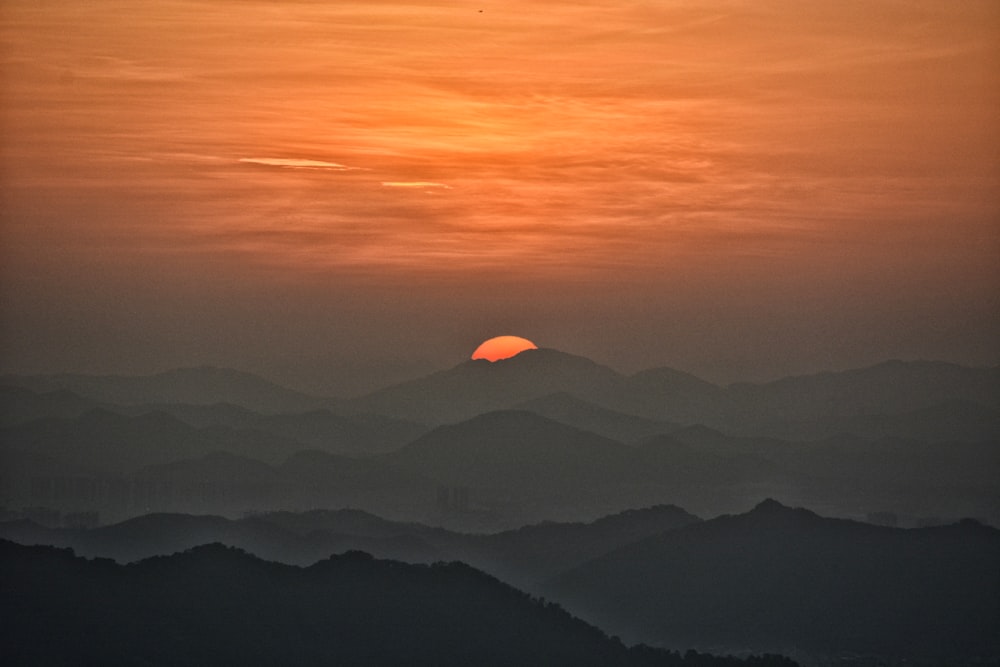 the sun is setting over a mountain range