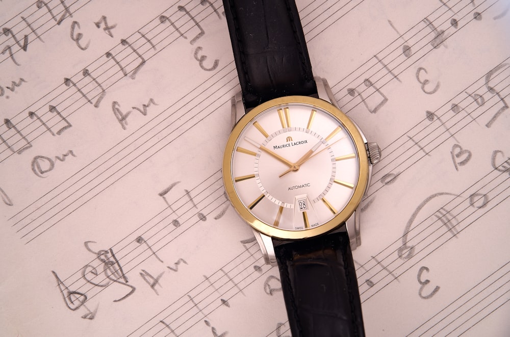 a watch sitting on top of a sheet of music