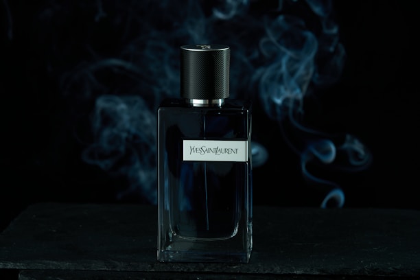 A sleek bottle of layered cologne with subtle smoke and citrus notes swirling around it.