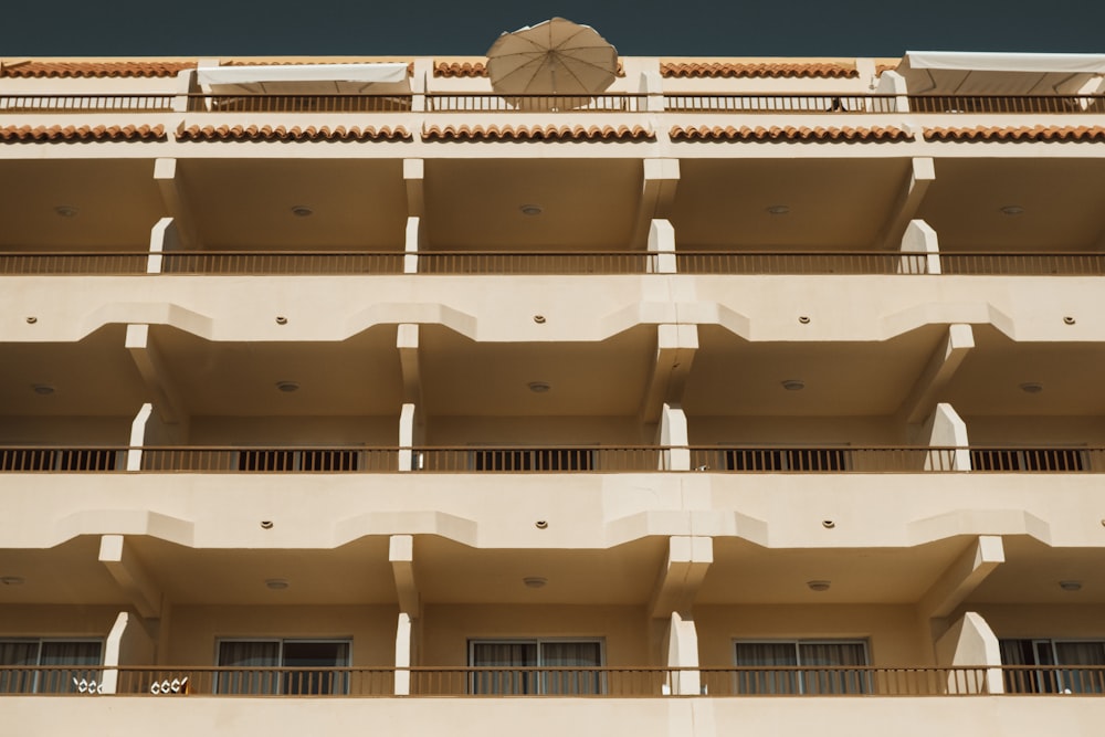 a tall beige building with balconies and an umbrella