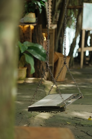 Rustic wooden swing in a blooming garden under a sunny sky