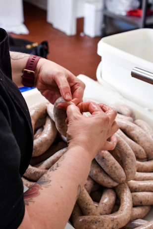 A cozy factory interior showing workers carefully preparing fresh sausages.