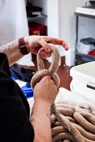 Artisan carefully preparing merguez sausages in a cozy kitchen.