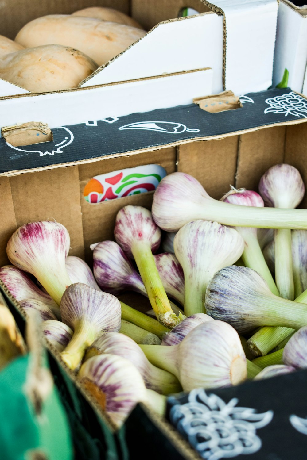 a cardboard box filled with onions next to a box of doughnuts