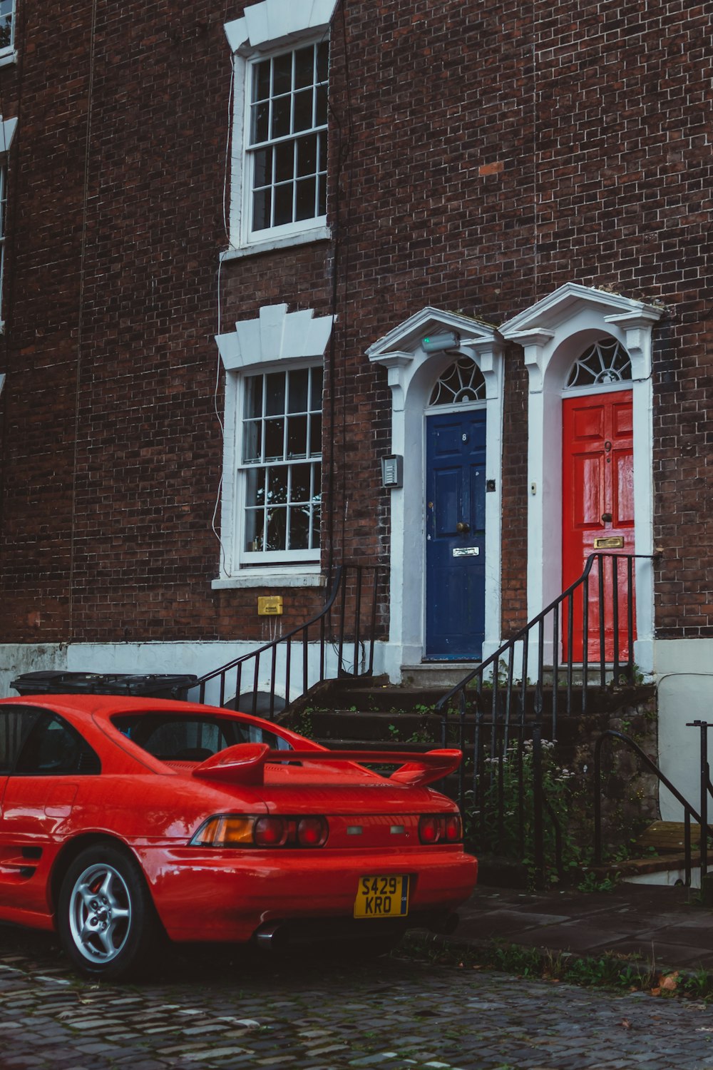 a red car parked in front of a brick building