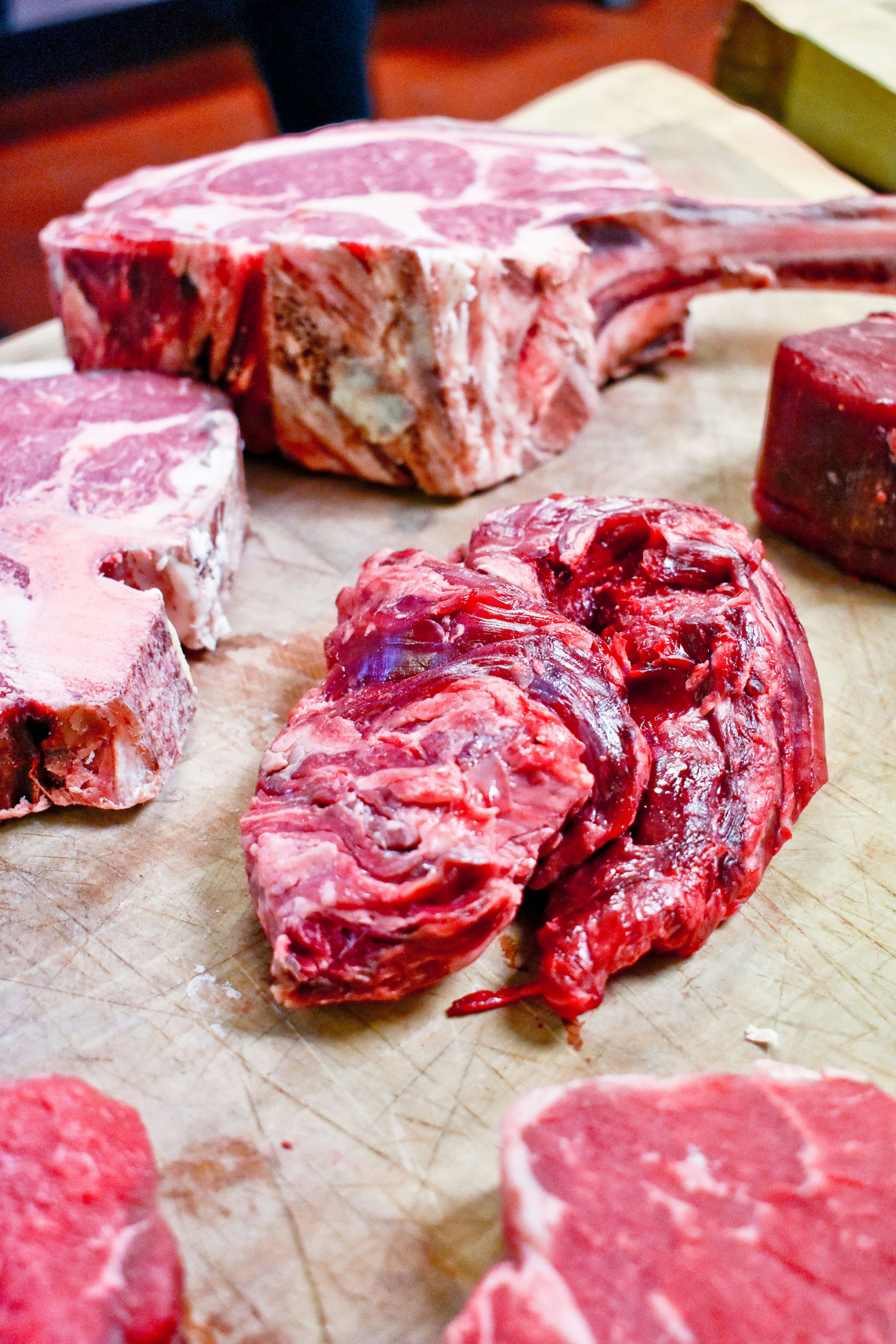 Premium cuts of fresh meat including steaks and chops arranged on a wooden cutting board