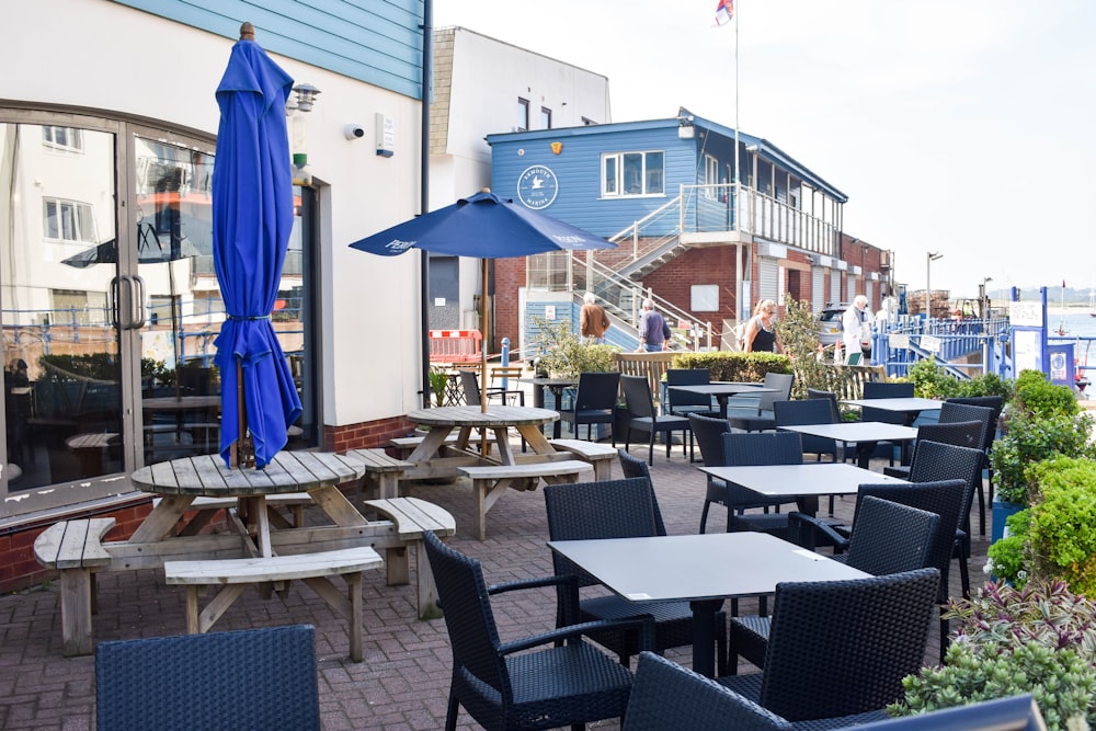 tables and chairs outside of a restaurant with umbrellas