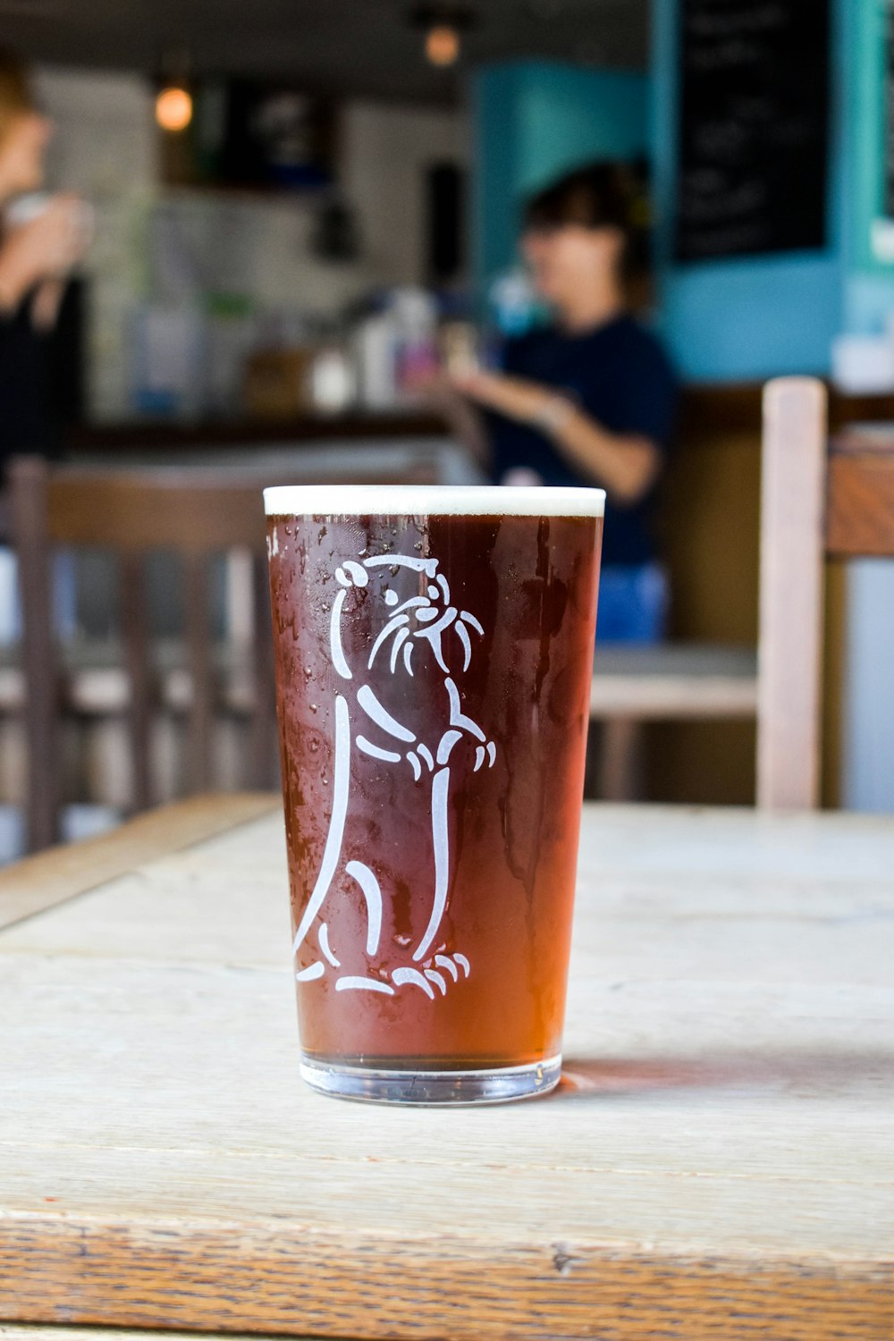 a glass of beer sitting on top of a wooden table