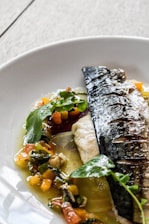 Close-up of a vibrant grilled salmon dish garnished with lemon wedges and fresh herbs on a rustic plate.