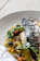 Close-up of a perfectly grilled fish fillet with lemon and herbs on a rustic plate.