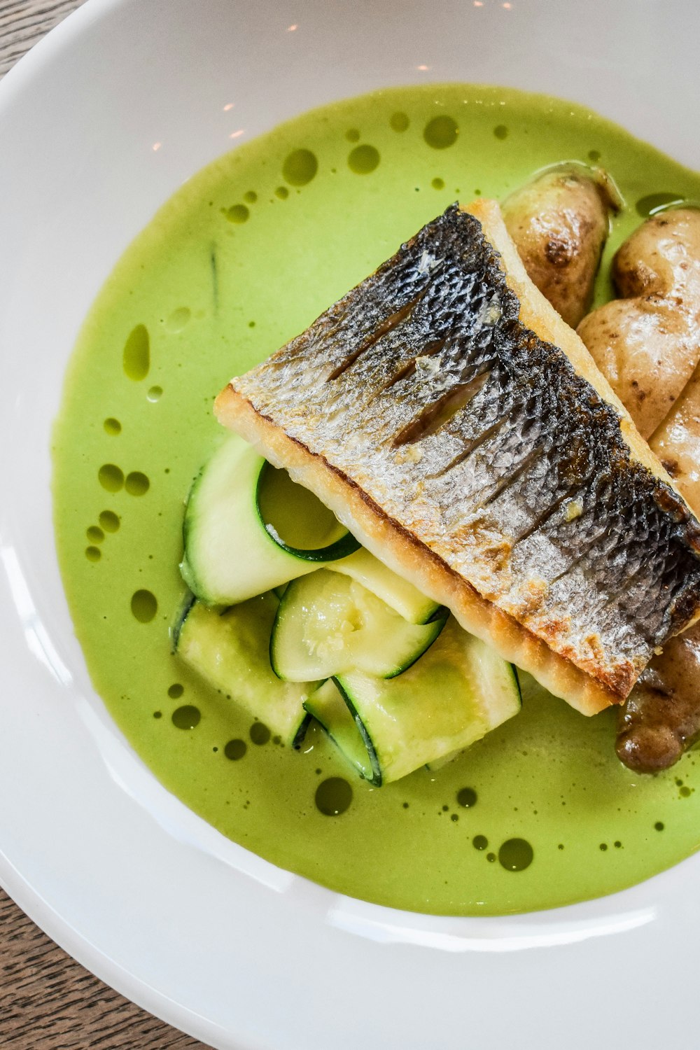 a white plate topped with a fish and cucumber