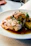 Close-up of a modern, stylishly plated chicken dish with fresh herbs.