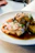 Close-up of a modern, stylishly plated chicken dish with fresh herbs.