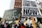 A protest scene with a crowd holding various signs. Prominent signs display messages such as 'Save Gaza' and 'Stand with Palestine! End the Occupation Now!' The atmosphere is filled with activism and solidarity.