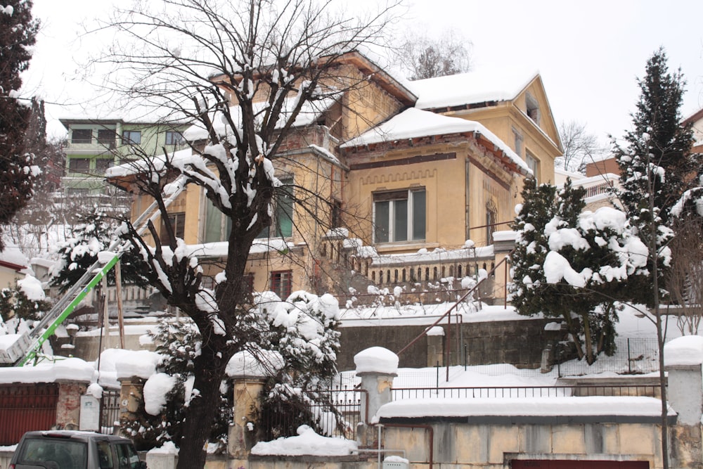 a house covered in snow next to a tree