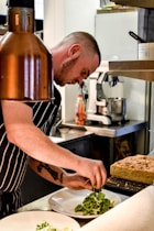 a man in a kitchen preparing food on a plate