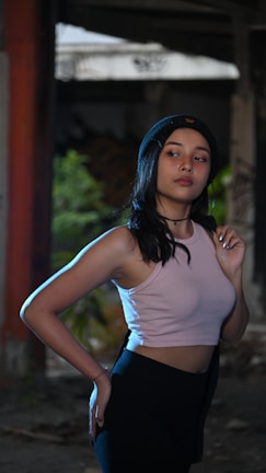 A young woman wearing a trendy pink cropped top and jeans posing outdoors.