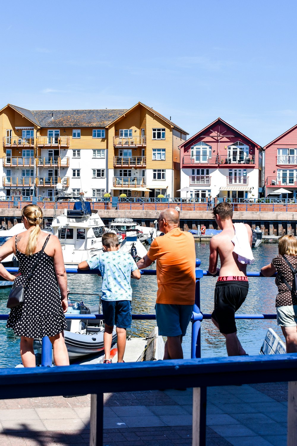 a group of people standing on a dock next to a body of water