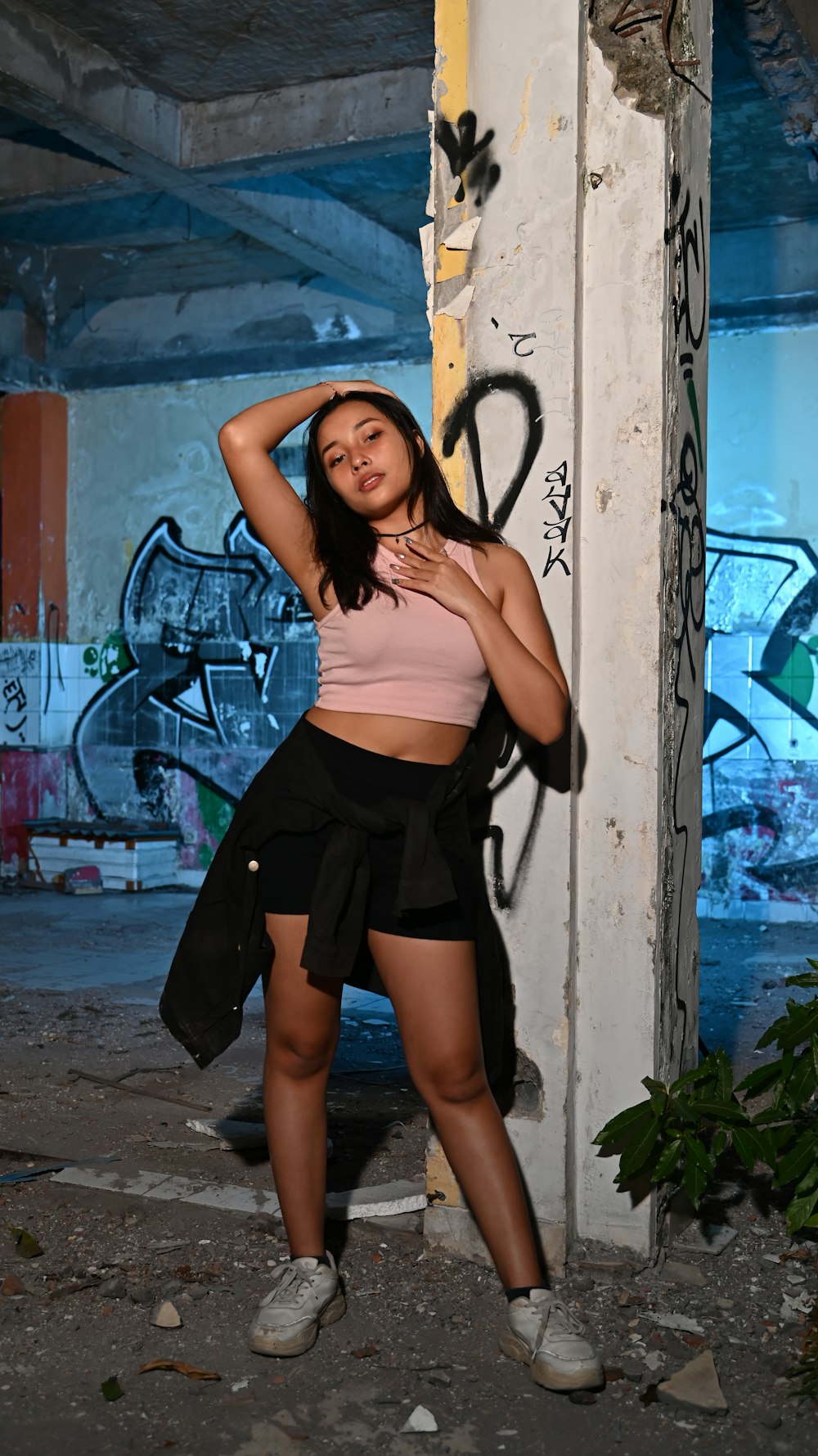 a woman in a pink top and black skirt leaning against a wall