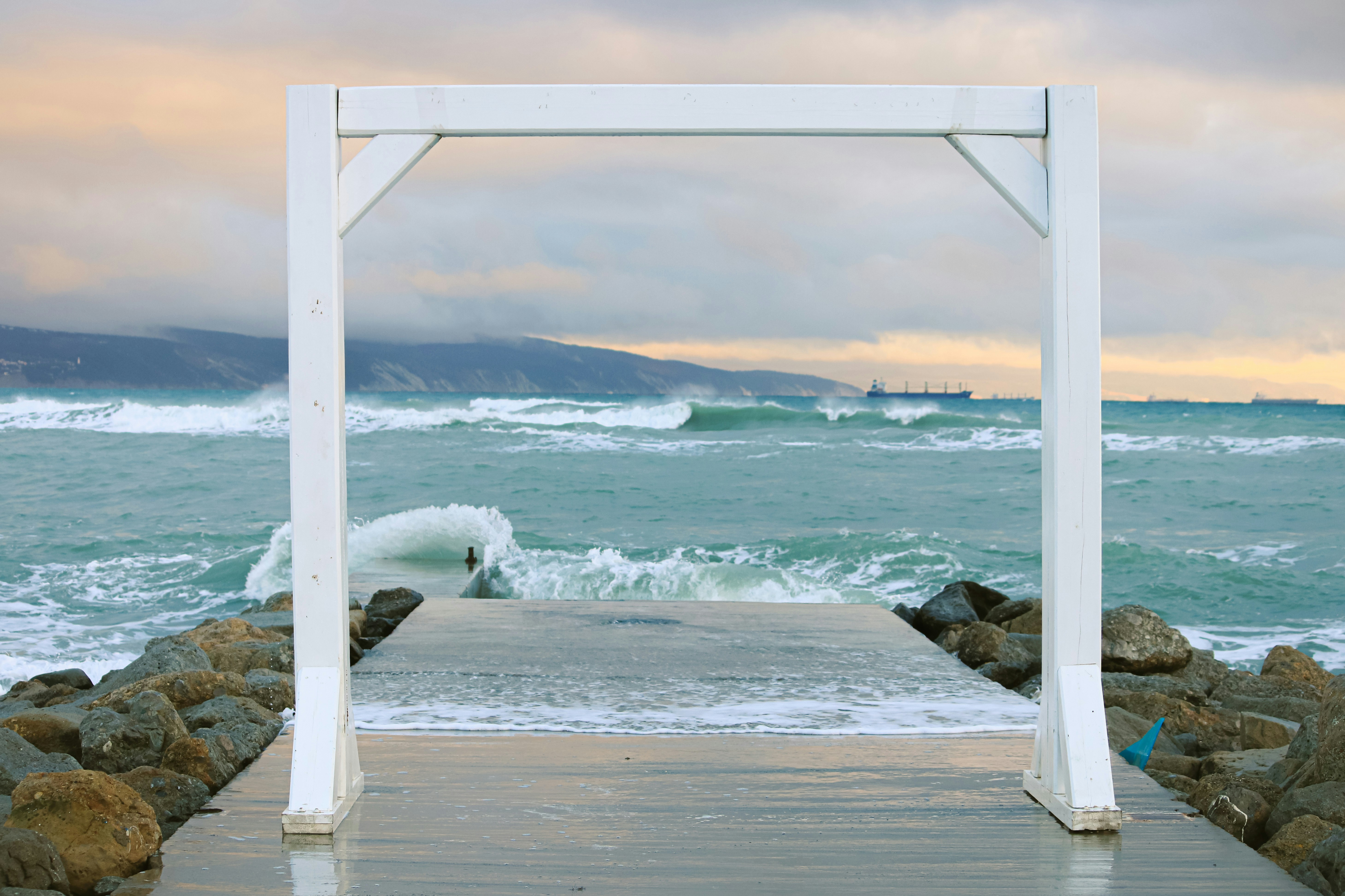 a wooden walkway leading to the ocean with waves coming in