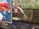 A billboard in a subway station with a colorful advertisement featuring a dish of food. Nearby, the iconic London Underground roundel with 'Paddington' is displayed, partially covered by a translucent plastic sheet. The wall behind appears worn with patches of peeling paint, giving a rustic and gritty look.