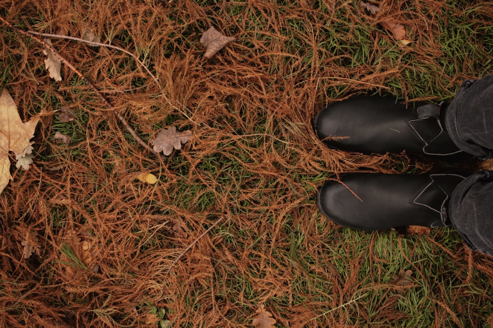 a person standing in the grass wearing black boots