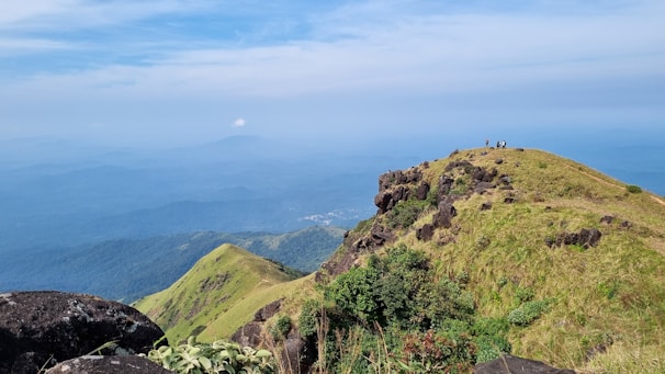 A scenic photo spot with visitors taking pictures against a backdrop of green hills.