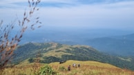 A group of friends sharing Nutriboost protein bars on a hiking trail overlooking rolling hills.
