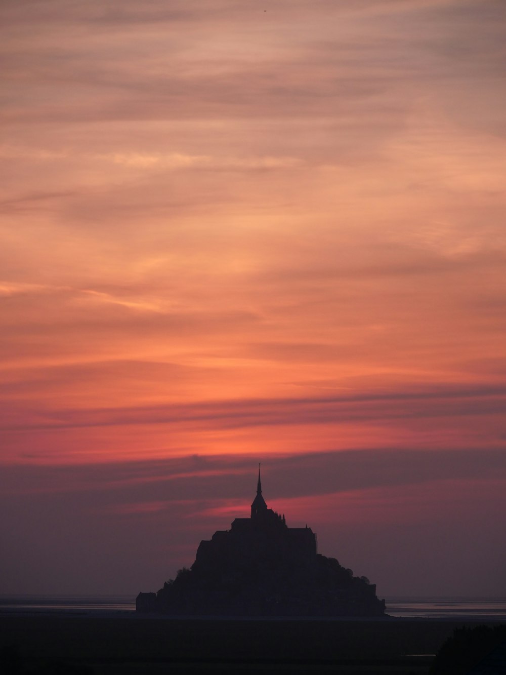 the sun is setting over a small island