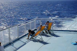Close-up of colorful ferry deck chairs with passengers enjoying the sea breeze.