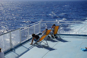 Close-up of colorful ferry deck chairs with passengers enjoying the sea breeze.