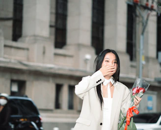 A delivery person holding a large bouquet of roses in front of a city skyline at sunset.
