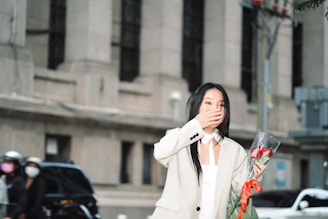 A delivery person holding a large bouquet of roses in front of a city skyline at sunset.