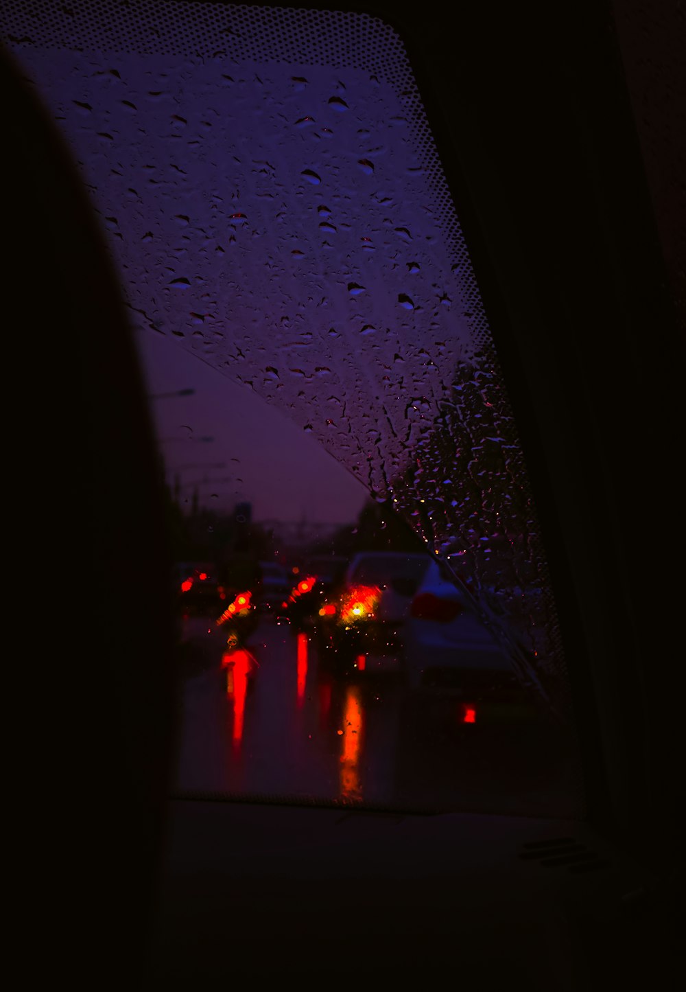 a view of a rain covered windshield at night