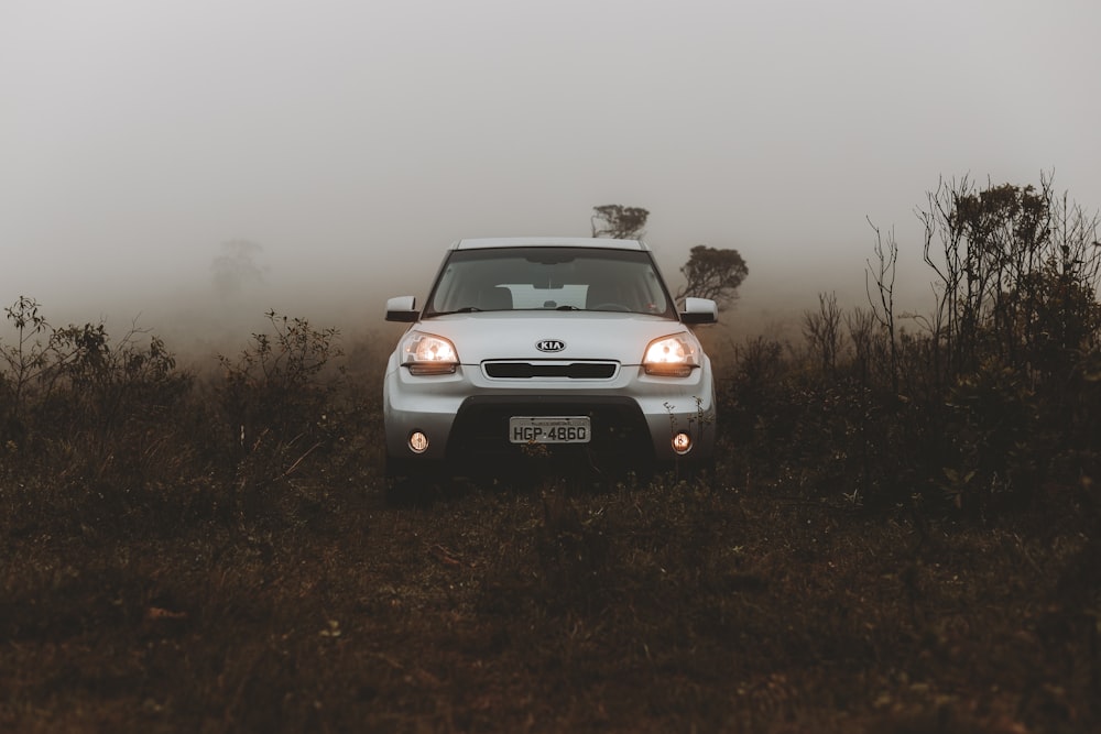 a white car driving through a foggy field