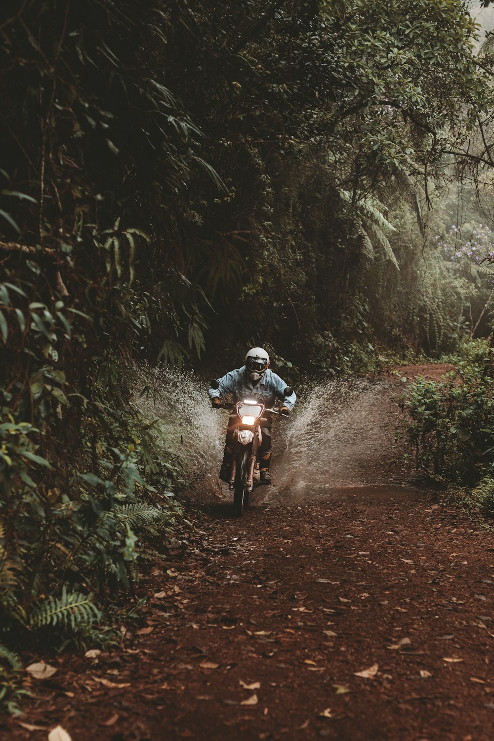 a man riding a dirt bike down a dirt road