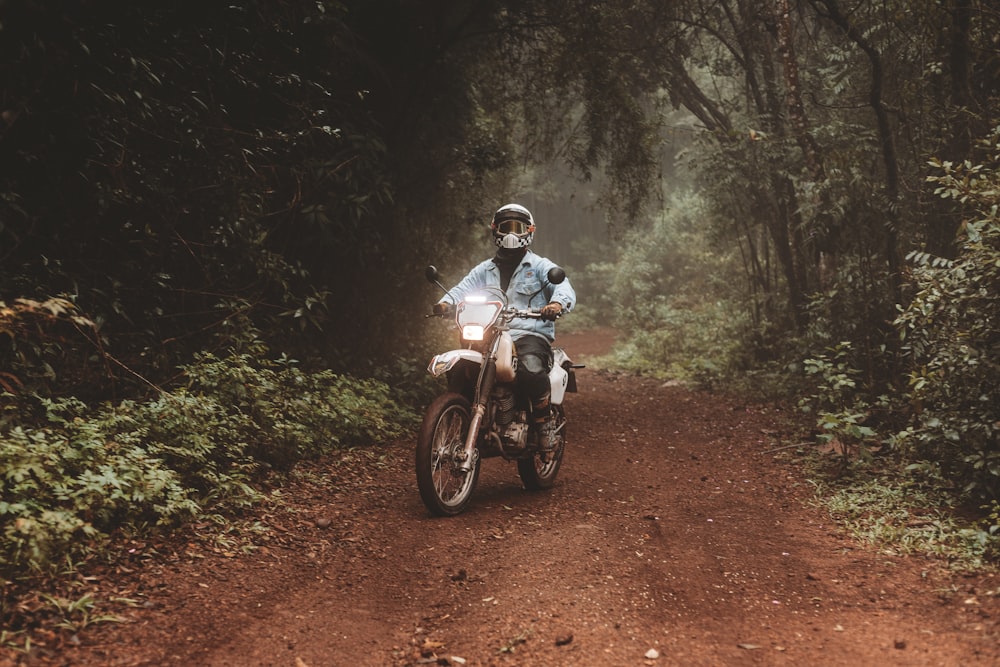 a man riding a motorcycle down a dirt road