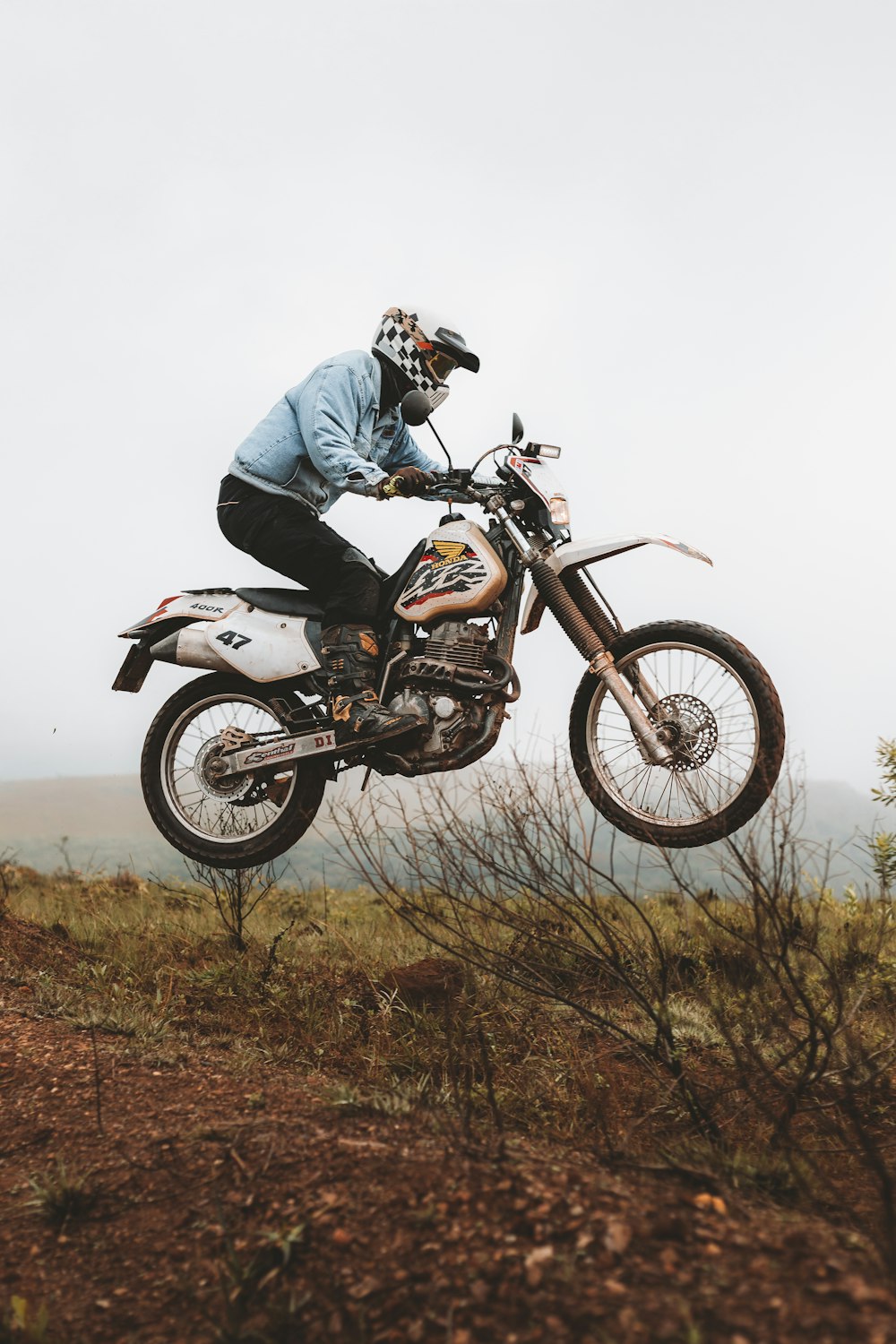 a man on a dirt bike jumping over a hill