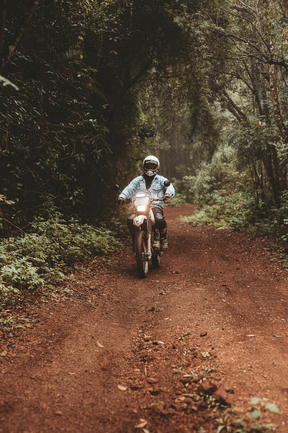 a man riding a motorcycle down a dirt road