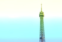 A stylized depiction of the Eiffel Tower dominates the frame, rising against a pastel gradient sky. The structure is infused with shades of green and blue, contrasting with the soft yellow and cyan sky, creating a surreal and artistic effect.