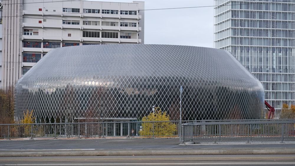 a large metal structure sitting next to a tall building